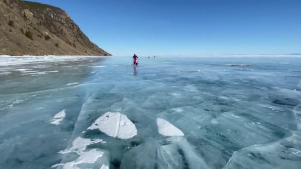贝加尔 Irkutsk Region Russia 2021年3月18日 一名妇女在冰冻的贝加尔湖冰上滑行 美丽的冬季风景 蓝色透明冰 裂缝很深 — 图库视频影像