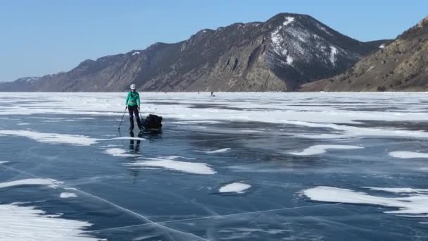 贝加尔 Irkutsk Region Russia 2021年3月17日 一个漂亮的女孩在冰冻的贝加尔湖冰上滑行 蓝色透明冰 裂缝很深 — 图库视频影像