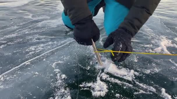 芝加哥 Irkutsk Region 俄克拉荷马州 2021年3月11日 一名身穿黑色手套的男子试图在冰冻的贝加尔湖冰上拧一个冰锥 握紧手 冬季远足 — 图库视频影像