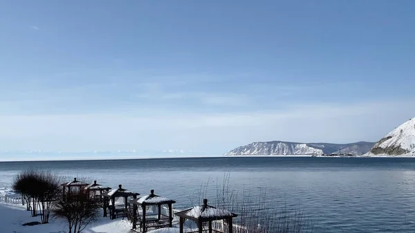 The non-freezing Angara River flows into the icy Lake Baikal. Northern landscape of frozen Lake Baikal. Irkutsk, Olkhon Island, natural landmark of Russia.
