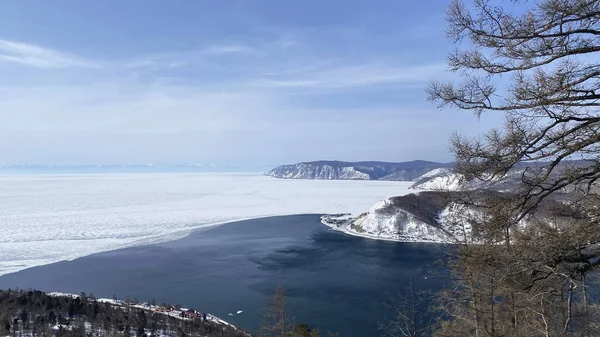 The non-freezing Angara River flows into Lake Baikal. Northern landscape of frozen Lake Baikal. Irkutsk, Olkhon Island, natural landmark of Russia. Bird\'s-eye view.