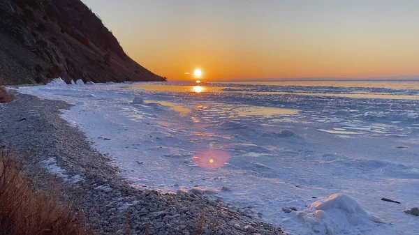 Amazing sunrise on the northern frosty Lake Baikal. Panorama of the northern landscape of the frozen lake. Ice hummocks, Olkhon Island.