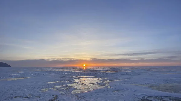 Amazing sunrise on the northern frosty Lake Baikal. Panorama of the northern landscape of the frozen lake. Ice hummocks, Olkhon Island.