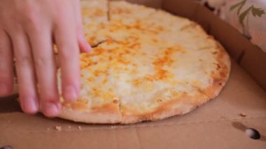 Çıplak gövdeli tüylü şişman bir adam yatakta oturur ve peynirli pizza yer. Genç adam bir dilim pizzadan çok erotik bir ısırık alır ve onu çiğner. Yatakta kahvaltı. Yakın plan..