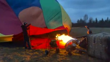 Puşkin, Rusya - 23 Nisan 2021: Büyük bir balonu havayla doldurma süreci. İki adam balonun altını tutuyor, böylece ocaktan çıkan sıcak hava balona giriyor..