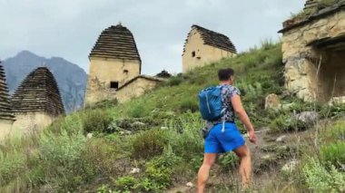 Küçük sırt çantalı bir turist antik akropolis boyunca yürüyor. Dargavs ölüler şehridir. Kuzey Osetya - Alania, Rusya.