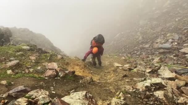 Стомлений Альпініст Помаранчевому Шоломі Великим Рюкзаком Піднімається Мотузці Вздовж Стежки — стокове відео