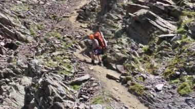 Bir turist, bir dağ yolu boyunca bir uçurumdan iniyor ve dikey korkuluklara tutunuyor. Kuzeyden, Rusya 'dan gelen Kazbek tırmanışı. Kafkasya 'da yürüyüş.