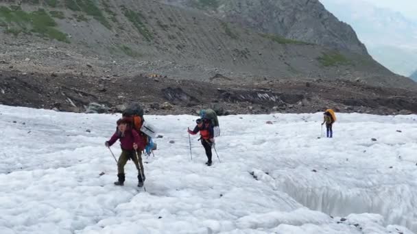 大きなバックパックを持つ観光客の小さなグループは マイリー氷河に沿って歩いている 北からカズベク登山 ロシアの側から コーカサスを横断するハイキング — ストック動画