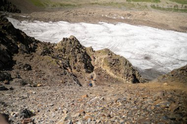 Yüksek uçurumdan aşağıdaki dağ turistlerine nefes kesici bir manzara. Rusya 'nın kuzeyinden Kazbek' e tırmanıyor. Kafkasya 'da yürüyüş.