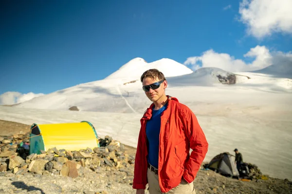 Portrait of a young male climber in mountain sunglasses against the background of Mount Kazbek. Climbing Kazbek from the north, from the side of Russia. Hike across the Caucasus.