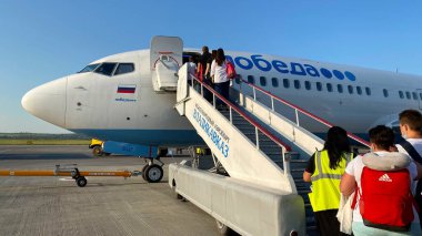 VLADIKAVKAZ, RUSSIA - 20 HAZİRAN 2021: İnsanlar Pobeda Havayolları 'nın uçağında yürüyen merdiven.