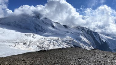 Kafkasya 'yı yürüyerek geçmek. Beyaz bulutlardaki karlı dağların çarpıcı manzarası. Kuzey Osetya 'nın güzel manzarası. Kuzeyden, Rusya 'dan gelen Kazbek tırmanışı.