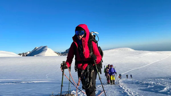 A climber in a ski mask goes up the hill. Mountain landscape of North Ossetia. Snow-capped mountains. Climbing Kazbek from the north, from Russia. Hike across the Caucasus.