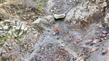 Kafkasya 'yı yürüyerek geçmek. Büyük bir sırt çantalı bir turist dağ yolundan aşağı ipe tutunarak iniyor. Kuzeyden, Rusya 'dan gelen Kazbek tırmanışı.