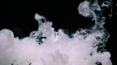 Siyah arka planda beyaz mürekkep bulutu. Kozmik büyü soyut arka plan. Suya bir damla beyaz mürekkep. Sıvı mürekkebin yavaş hareketi.