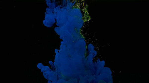 Blue and yellow watercolor ink in water on a black background. Blue-yellow cloud of ink. Cosmic magic background. Waves and drops of blue-yellow colors. Beautiful abstract background.