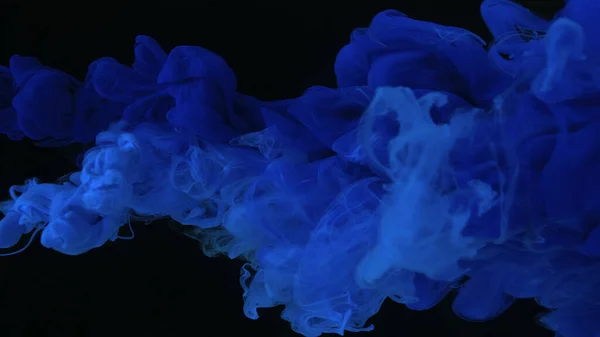 Drops of blue ultramarine ink in water. Blue watercolor paints in water on a black background. Awesome abstract background. Beautiful wallpaper for your desktop. Ultramarine cloud of ink on a black background.