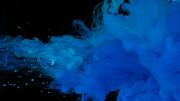 Beautiful wallpaper for your desktop. Blue cloud of ink on a black background. Drops of blue ink in water. Blue watercolor paints in water on a black background. Awesome abstract background.