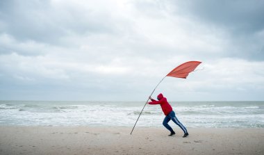 Rüzgar ile mücadele fırtınalı denizde kişi kıyısında. Kırmızı bayrak Rüzgar gücünü gösterir.