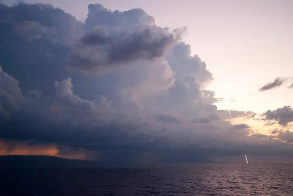 The sunset view of a stormy cloud with a lightning near Jamaica\'s coastline.