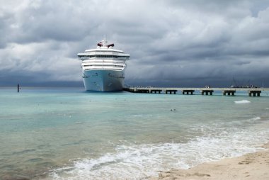 Turistik bir sahil manzarası ve arka planda demirlemiş bir yolcu gemisi Grand Türk adasındaki bulutlu gökyüzünün altında (Turks ve Caicos Adaları)).