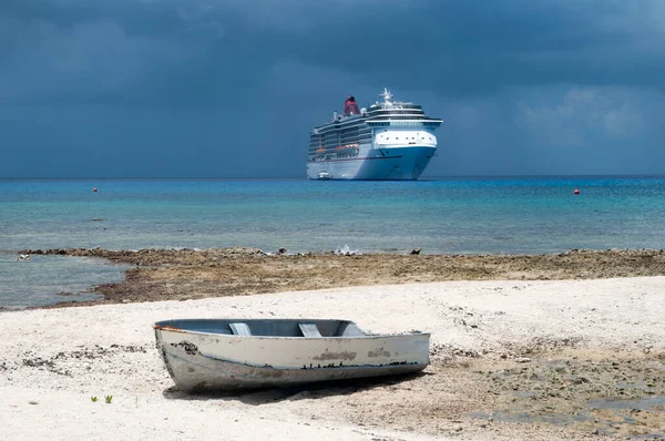 Büyük Cayman Adası 'ndaki eski bir teknenin manzarası. Yedi Mil Sahili ve arka planda bir yolcu gemisi. Kara yağmurlu gökyüzünün altında.). 