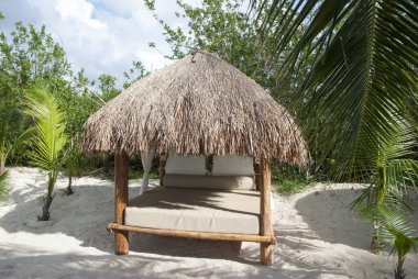 Cozumel Adası plajında saman çatısı olan boş bir masaj yatağı manzarası (Meksika).