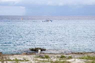 Geçen bir teknenin manzarası ve arka planda yağmur bulutları (Cozumel, Meksika).
