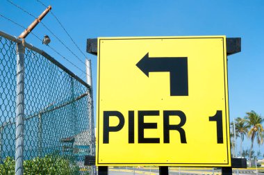 Yön tabelası ve Grand Bahama Adası limanında bir telin üzerinde oturan küçük bir kuş..