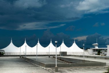 Miami limanının yüksek kontrastlı parkı ve karanlık bulutlu gökyüzünün altında bir yolcu gemisi terminali manzarası (Florida).