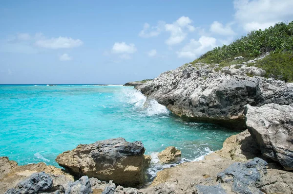Half Moon Cay 'in dik kayalık kıyı şeridi ve turkuaz renkli sularının manzarası (Bahamalar). 
