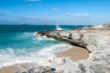 Arkasında dalgalar ve endüstriyel gemilerle aşınmış Grand Bahama adası kıyı şeridi manzarası.