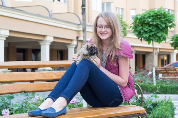 Mädchen mit Hund auf einer Bank — Stockfoto