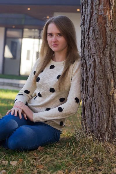 bir ağacın yanında oturan kız