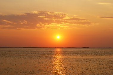 Günbatımı turuncu tonlarında su üzerinde