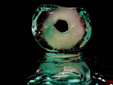 Karanlıkta parlak bir buz kütlesi içinde bir delik olan dış uzaydaki bir nesne gibi.