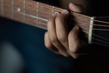 Akustik gitarda G akoru pozisyonları yapıyor.