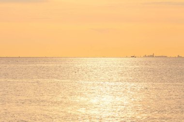 Yazın gün batımında, batı denizinin sularının üzerinde turuncu bir gökyüzü olan Zeeland 'in Hollanda kıyılarında harika bir deniz manzarası.