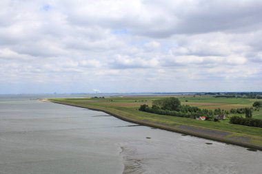 Batı Denizi 'ndeki hava manzarası ve Zeeland ve Antwerp' teki Hollanda kıyılarındaki tarlalar ve arkasında bulutlar olan mavi bir gökyüzü.