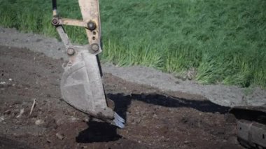 Kazı kovası yakın plan. Yol yapımı. Kazıcı yol kenarını kovayla düzleştiriyor..