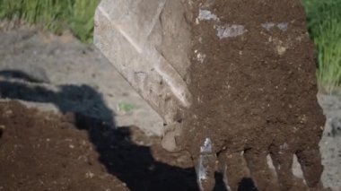 Kazı kovası yakın plan. Yol yapımı. Kazıcı yol kenarını kovayla düzleştiriyor..