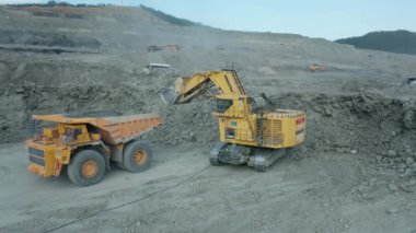Rusya, Uglegorsk, 7 Temmuz 2021. Komatsu PC4000 kazıcı maden sahasındaki BelaZ çöp kamyonuna cevher yüklüyor..