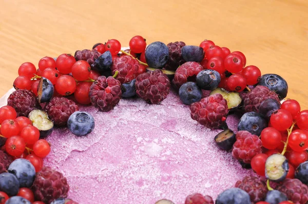 Festive cake, blueberry and blackberry sponge cake with cream cheese inside on a plate on a wooden table, horizontal view from above.