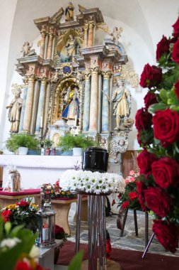 Kilisedeki cenaze gününde, etrafı papatya ve güllerle çevrili.