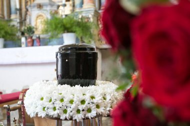 Kilisedeki cenaze gününde, etrafı papatya ve güllerle çevrili.
