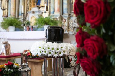 Kilisedeki cenaze gününde, etrafı papatya ve güllerle çevrili.