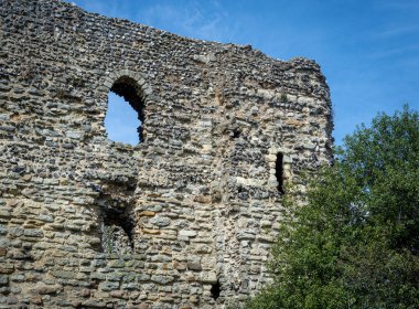 Canterbury Şatosu, mavi gökyüzü ve önplanda ağaçla aydınlık bir bahar gününde harabeye döner..