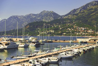 Denizde yatlar, arka planda dağlar. 