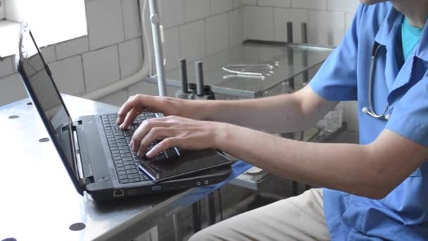 Doctor sitting at desk and typing on laptop — Stock Video